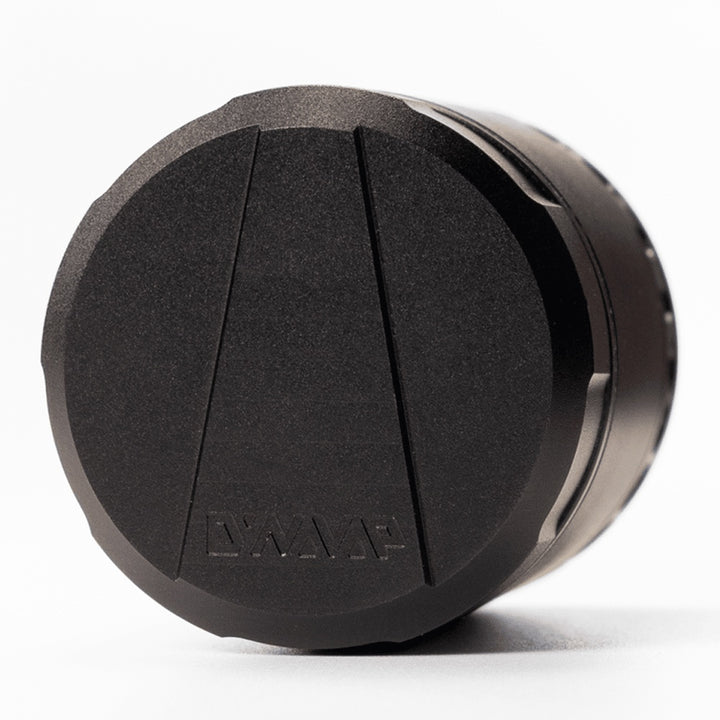 Tapa magnética del grinder DynaVap DynaGrynd con textura granulada y logo de la marca